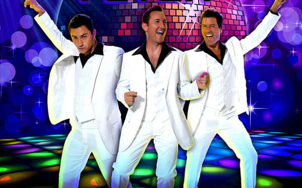 Three male singers in our 70s themed trio performance posing happily in front of dance floor with disco ball in background | Altus Entertainment